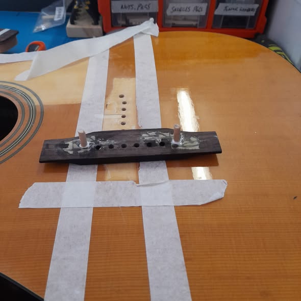 Epiphone acoustic top with the bridge removed and taped off, glue residue cleaned in preparation for a bridge reglue