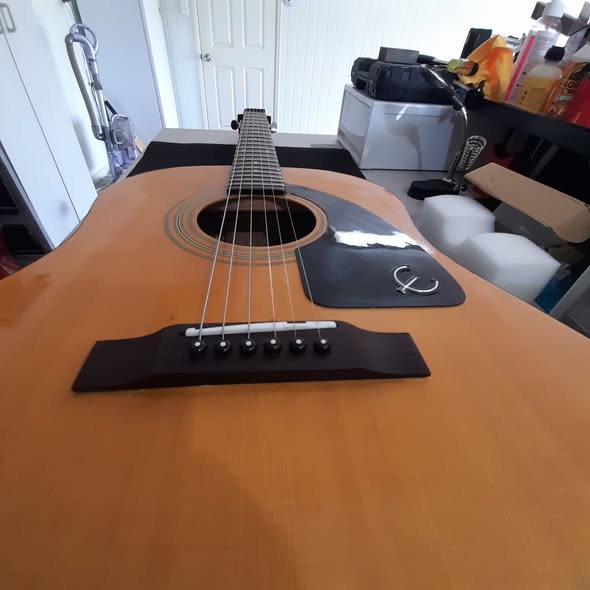 Epiphone acoustic after bridge reglue and restring, viewed down the body with a clean bridge and new strings seated