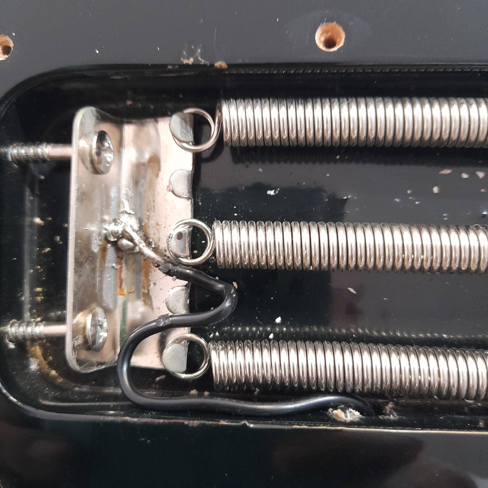 Tremolo spring cavity after repair with a clean solder joint and new insulated ground wire neatly routed to the claw